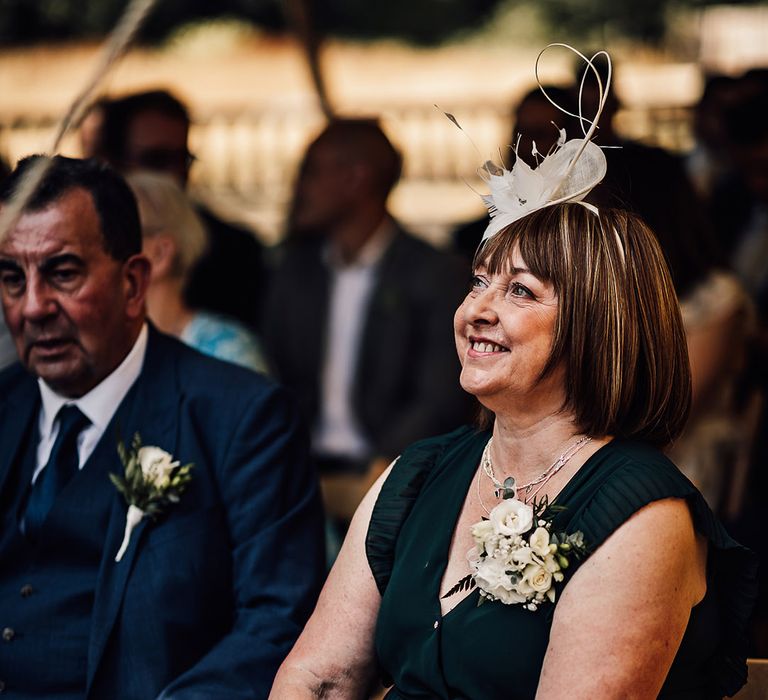 Wedding guest sits in a green dress and fascinator for the wedding 