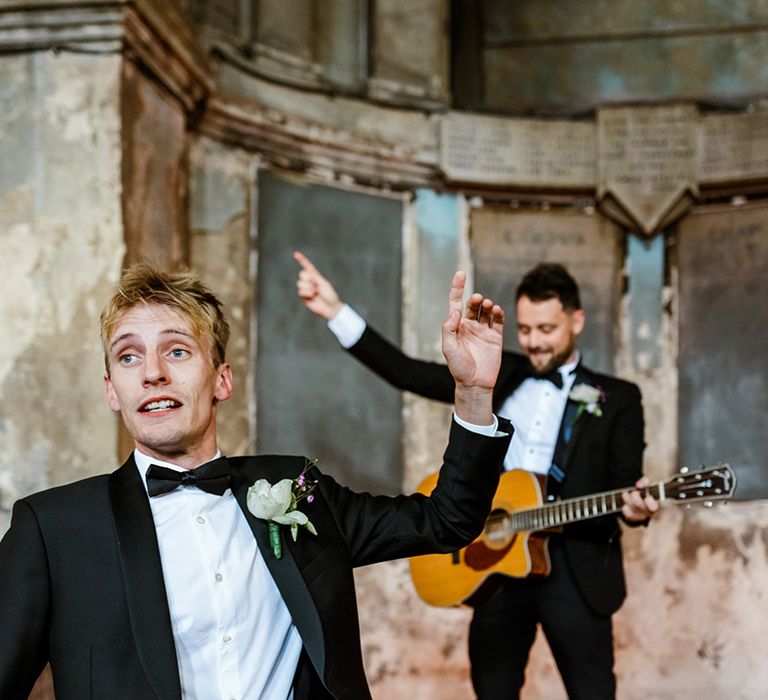 Wedding guests in black tie sing during wedding ceremony 