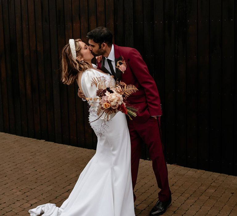 Crumplebury wedding with the bride and groom sharing a kiss in front of the modern black cladding 