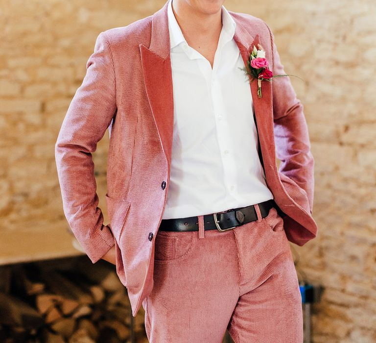 Groom wearing pink corduroy suit with pink and red rose, foliage and dried flower boutonniere 