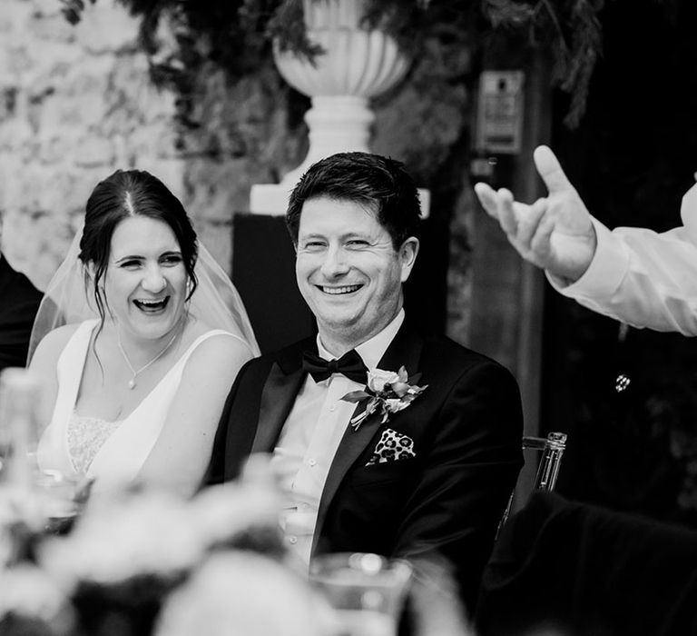 Groom in black tie sitting at the top table with the bride for the wedding reception 