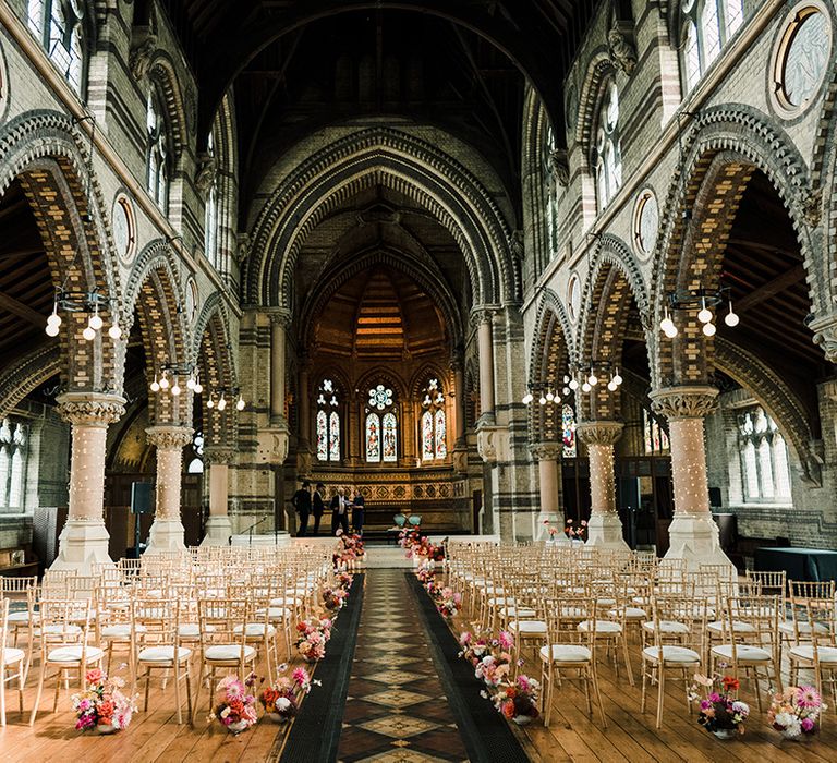 St Stephen's Hampstead church complete with colourful florals lining the aisle alongside wooden chairs 