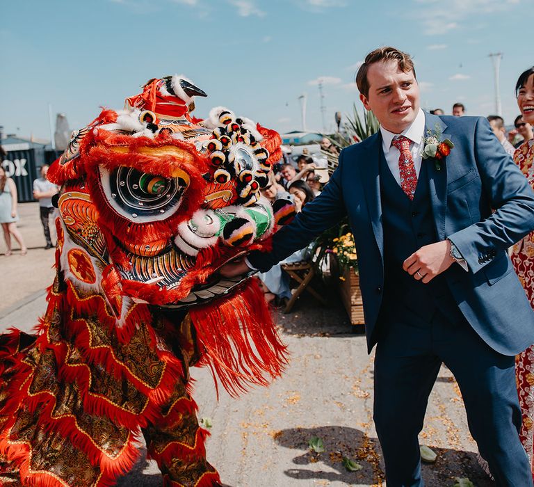 Groom places red envelope in the mouth of dragon during Lion Troupe Dance 