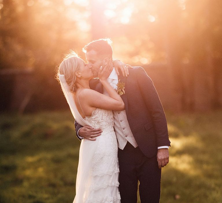 The bride and groom share a kiss during the sunset for their fun botanical wedding in Shropshire 