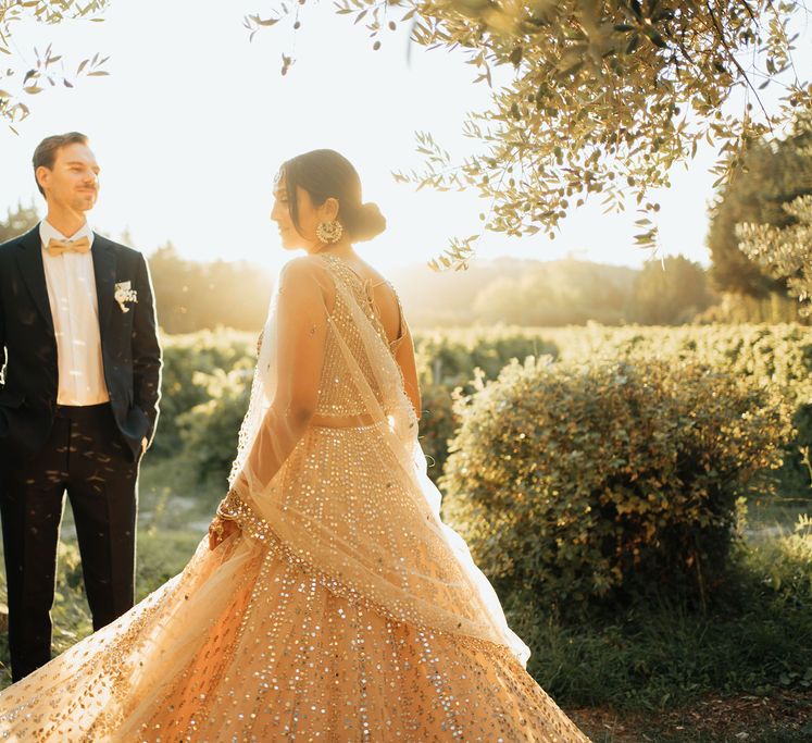 Groom in a black tuxedo twirling his bride in a sparkly wedding dress at their destination wedding 