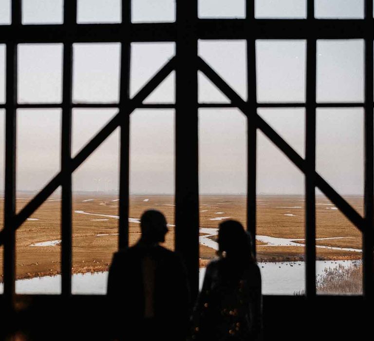 Bride and groom looking out at Elmley Nature Reserve wedding venue - Kent wedding venues 