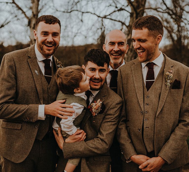 Groomsmen in matching grey suits and red ties with the page boy wearing a similar waistcoat and flat cap 