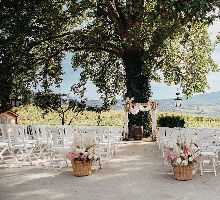 outdoor wedding ceremony at Porto Vineyards with fresh and dried flowers in baskets and wooden frame altar 