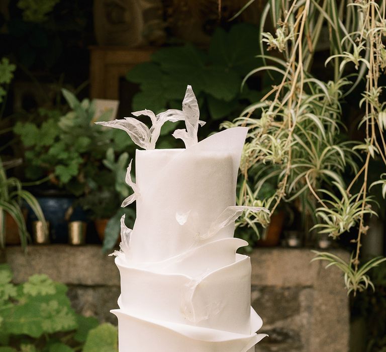 Three tier all white wedding cake with delicate petal style detail 