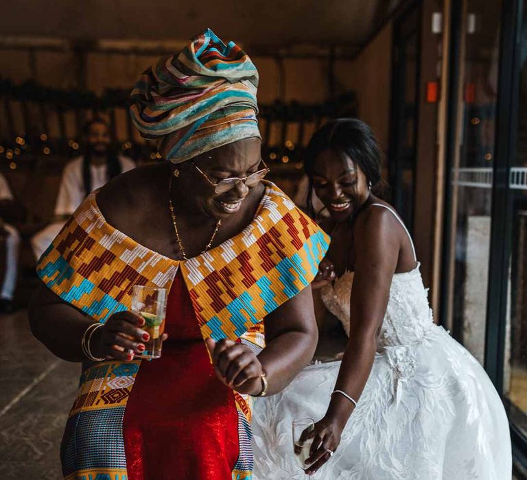 Bride in sweetheart neckline lace wedding dress and wedding guest in traditional Ghanaian wedding outfit at Lains Barn wedding