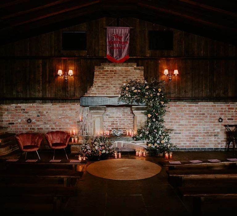 Reception room of Willow Marsh Farm Loughborough with tapered candles, fabric wedding banners, red velvet chairs and large exposed brick fireplace 