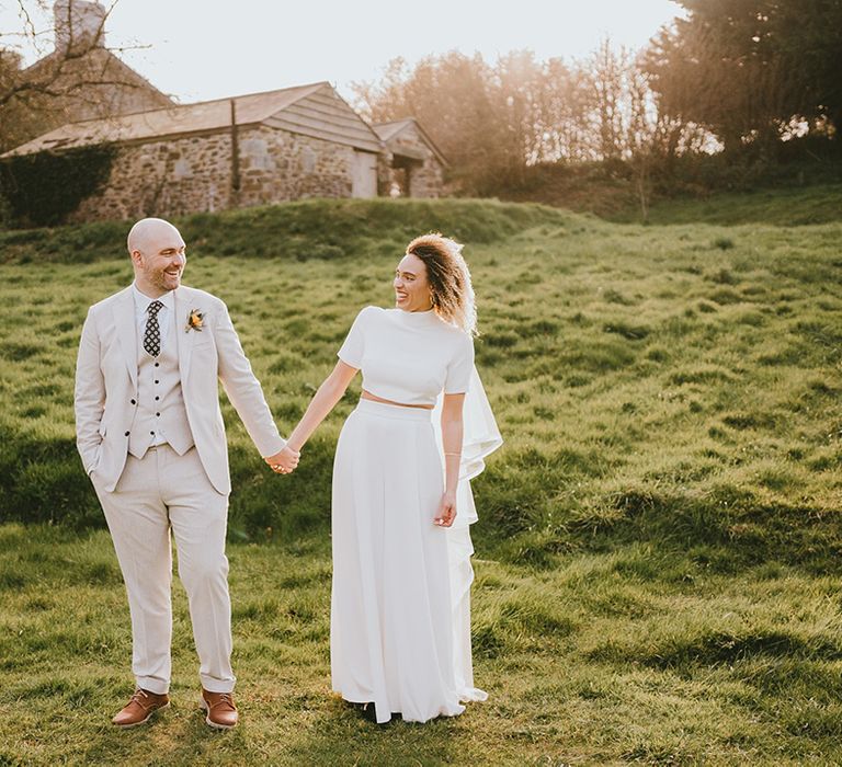 Bride in custom Jesus Peiro wedding two piece set with the groom in cream three piece suit 