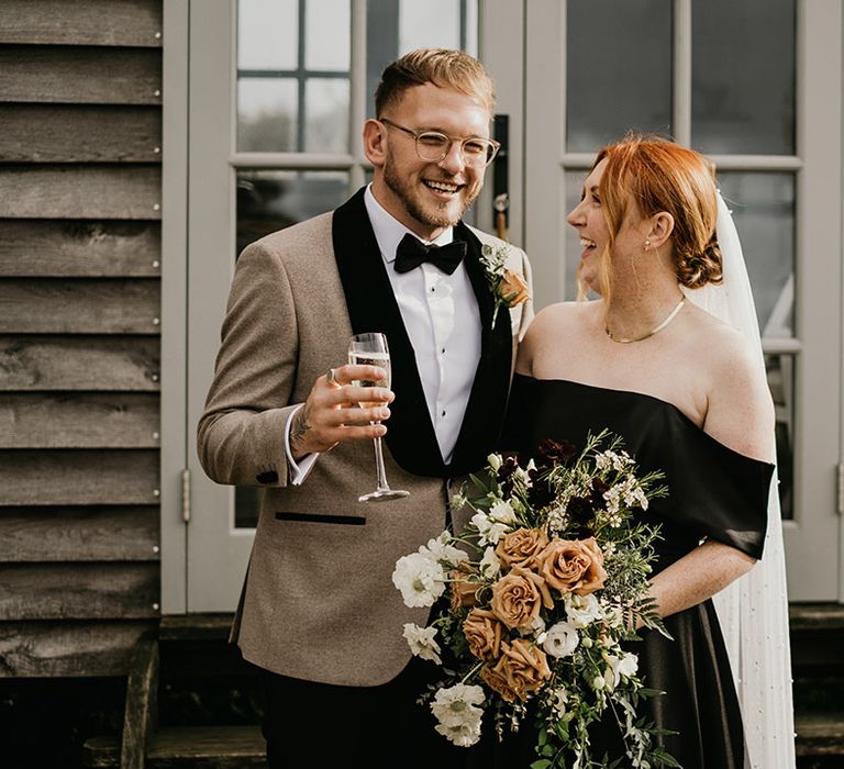 Cascading orange wedding bouquet held by bride in black bridal gown 