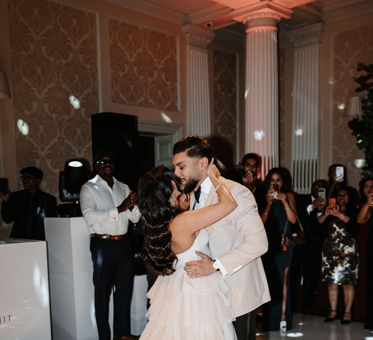 The bride and groom in their wedding reception outfits share their first dance together 