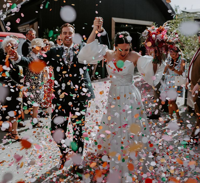 Colourful confetti moment for bride and groom after their wedding ceremony 