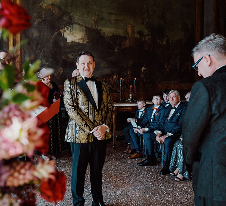 Groom in black and gold tuxedo at gay wedding ceremony at Ca'Sagredo hotel wedding venue 