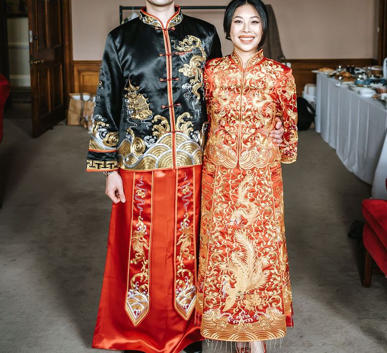 Bride and groom in traditional red, black and gold Chinese wedding attire for multicultural wedding 