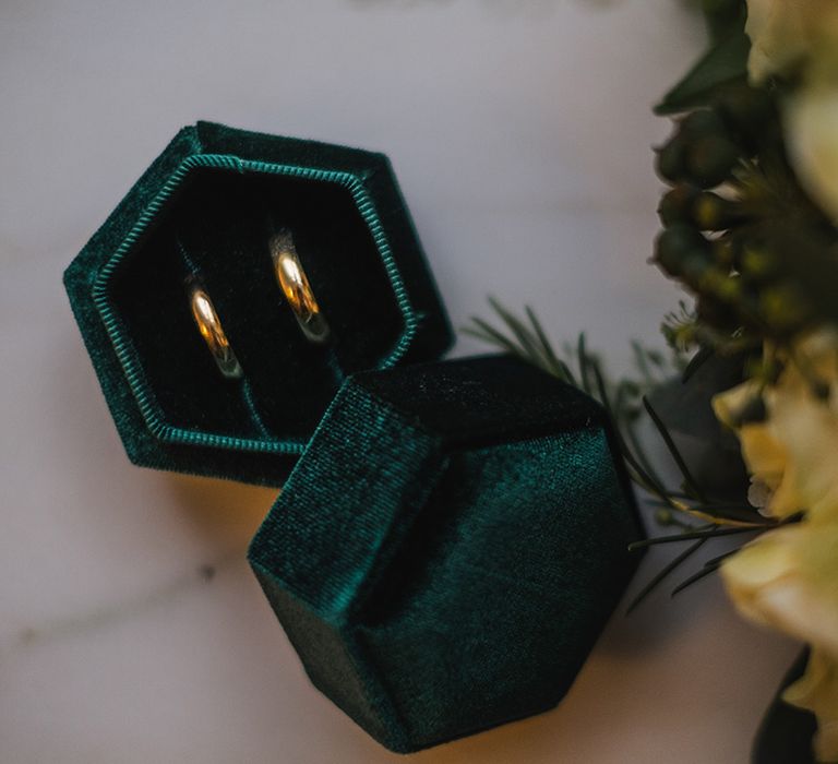 Green velvet ring box with gold wedding bands for bride and groom 