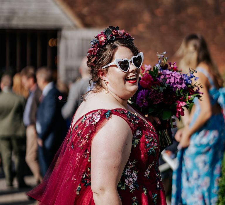 Retro wedding sunglasses with boho flower crown with bold red wedding dress at barn wedding 