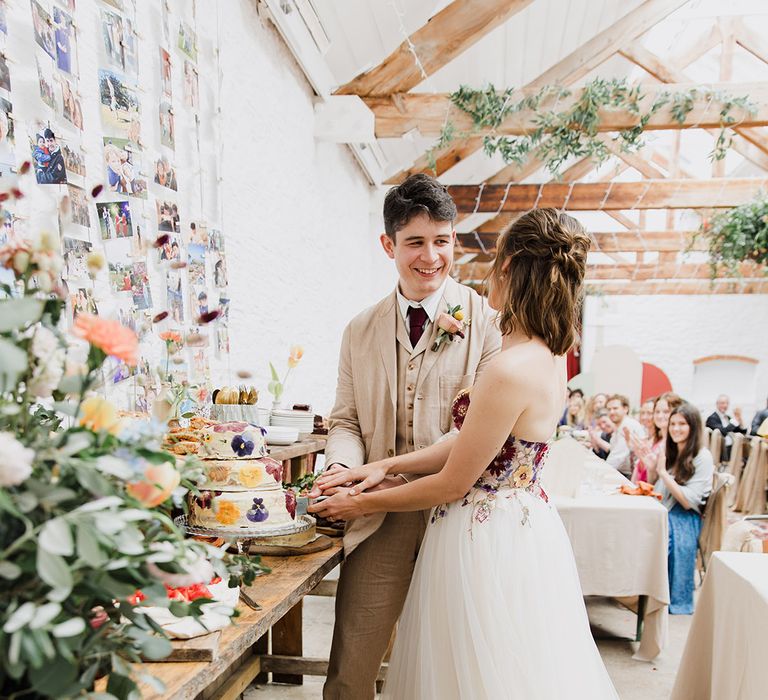 The bride and groom cut their homemade wildflower pressed wedding cake 