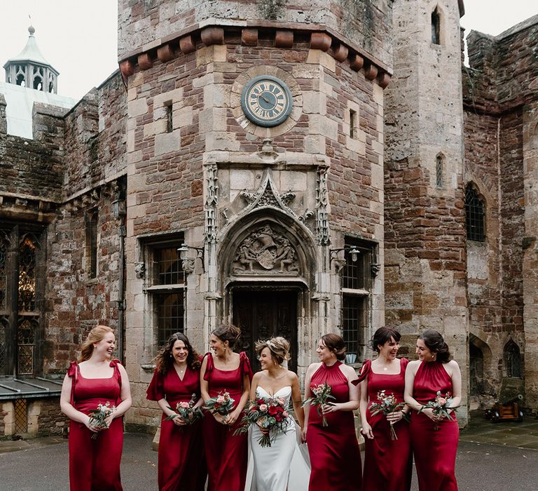 Bridal party wearing red bridesmaid dresses for the traditional winter wedding with matching red and light pink rose bouquets 