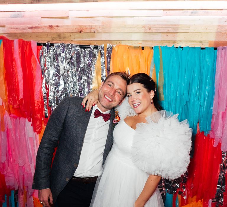 Bride in tulle puff sleeve wedding reception dress smiling with groom 