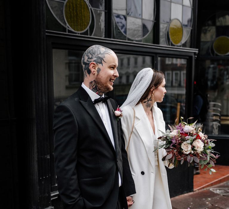 Stylish bride and groom in tuxedo and jumpsuit at Intimate Brighton wedding 