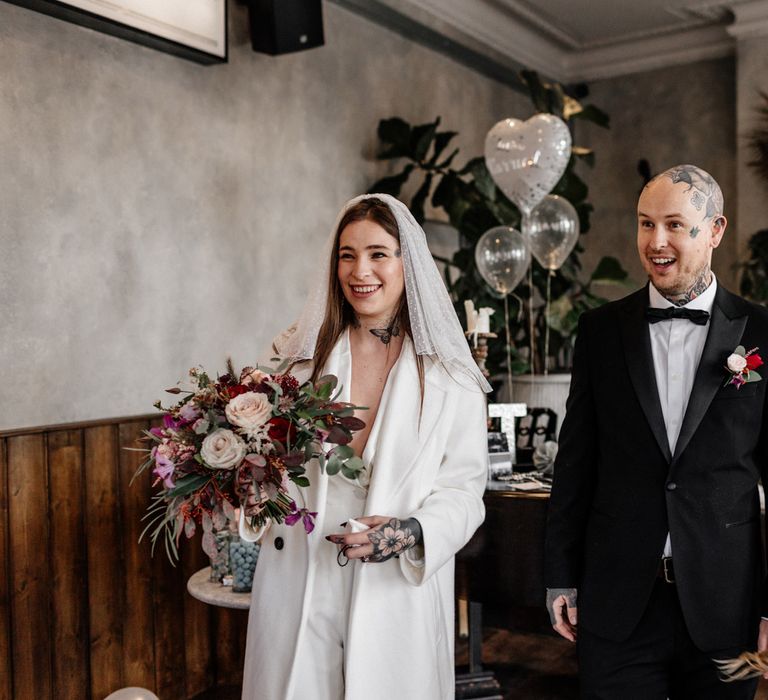 Bride in jumpsuit and polka dot veil and groom in tuxedo 