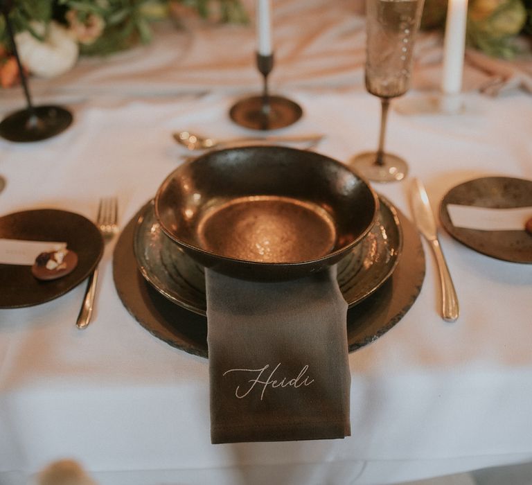 Place setting with coloured table ware and personalised embroidered napkins 