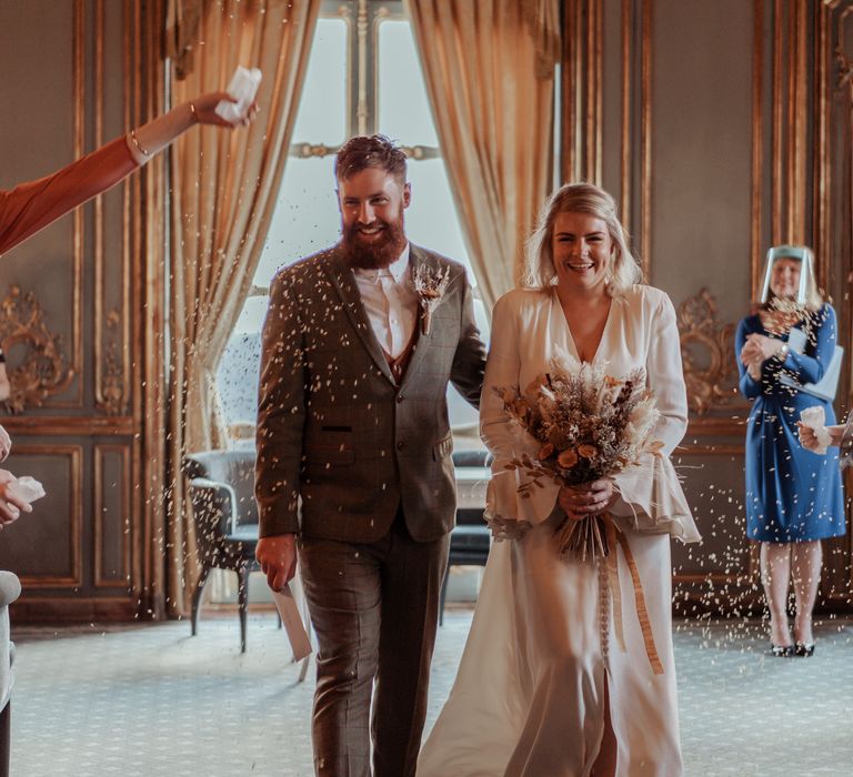 Bride & groom laughing through confetti 