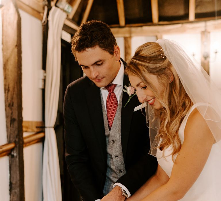 Bride and groom cutting the single tier wedding cake 