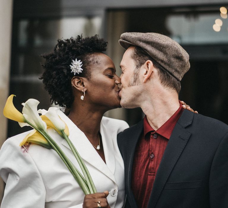 West African bride with short hair kissing her Franco-American groom in a fat cap 