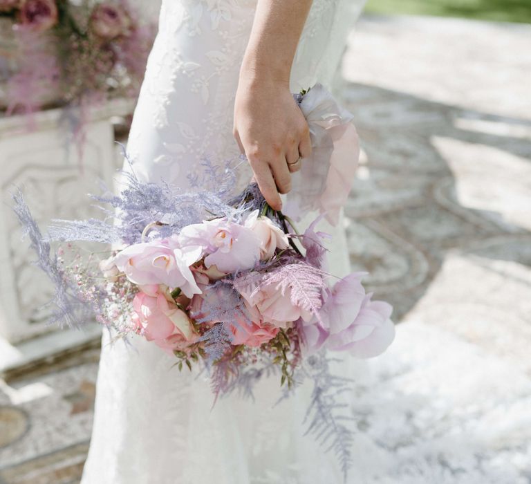 Bride carries lilac bouquet whilst wearing lace gown