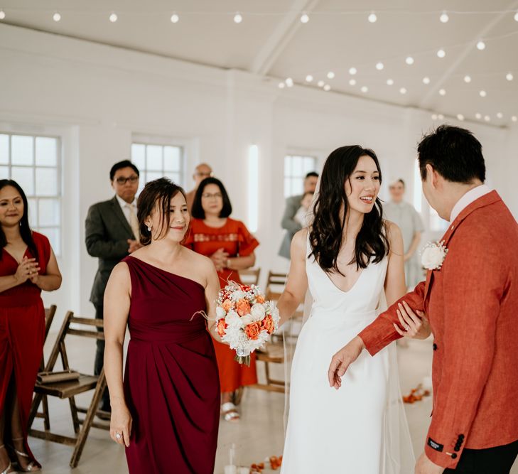 Father of the bride walking his daughter down the aisle in a brunt orange blazer