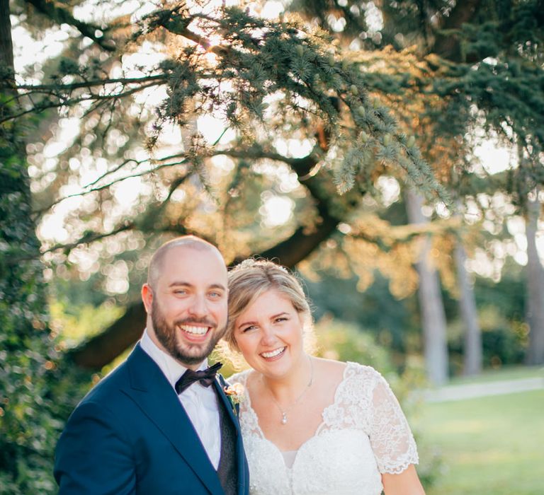 The bride and groom arm in arm smiling after their outdoor wedding ceremony