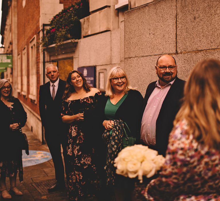 Bride & groom stand outdoors with wedding party after marrying 