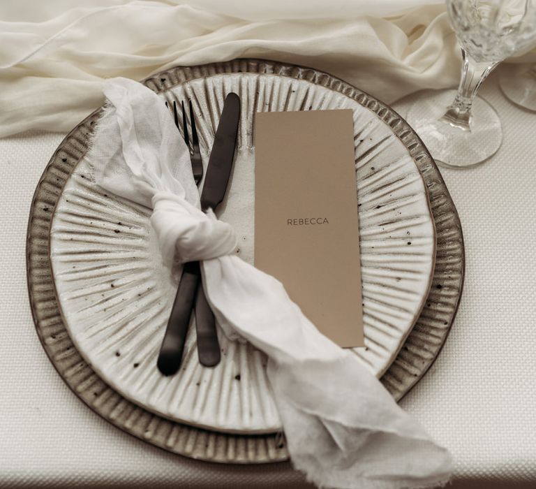 Place setting with patterned tableware, black cutlery and linen napkin