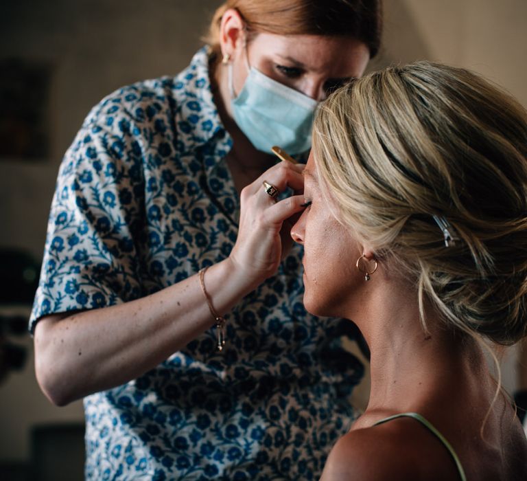 Bride having her makeup done with a relaxed updo wedding hairstyle