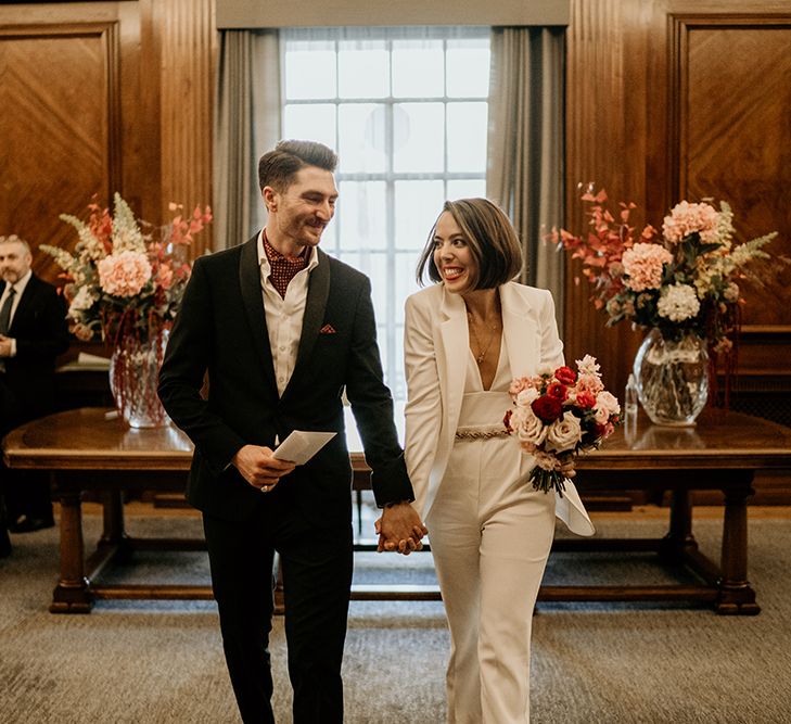 Bride & groom hold hands as they leave their wedding ceremony