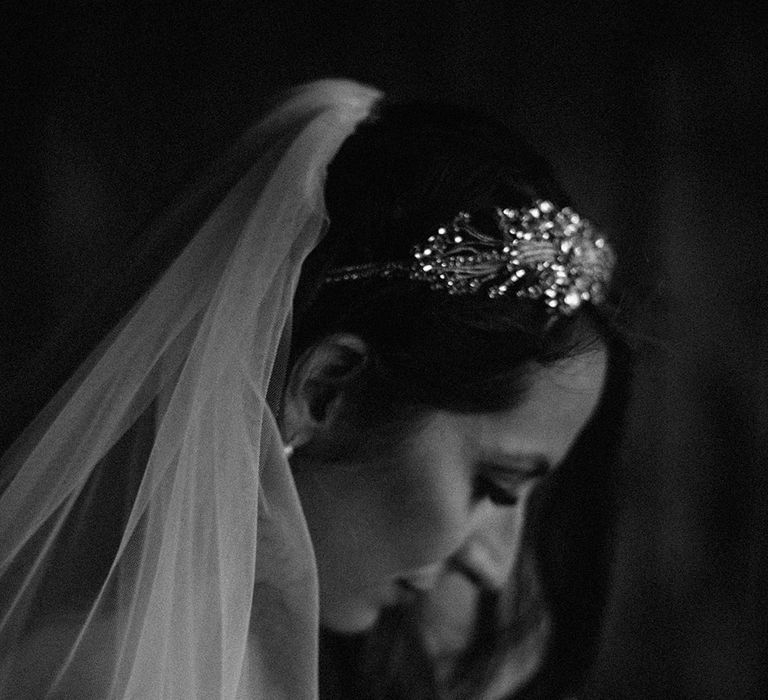 Black & white image of bride as her veil frames face and she looks down