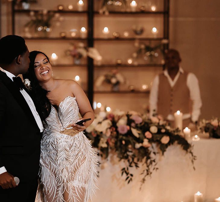 Groom kissing his bride's forehead as they deliver their wedding speeches together 