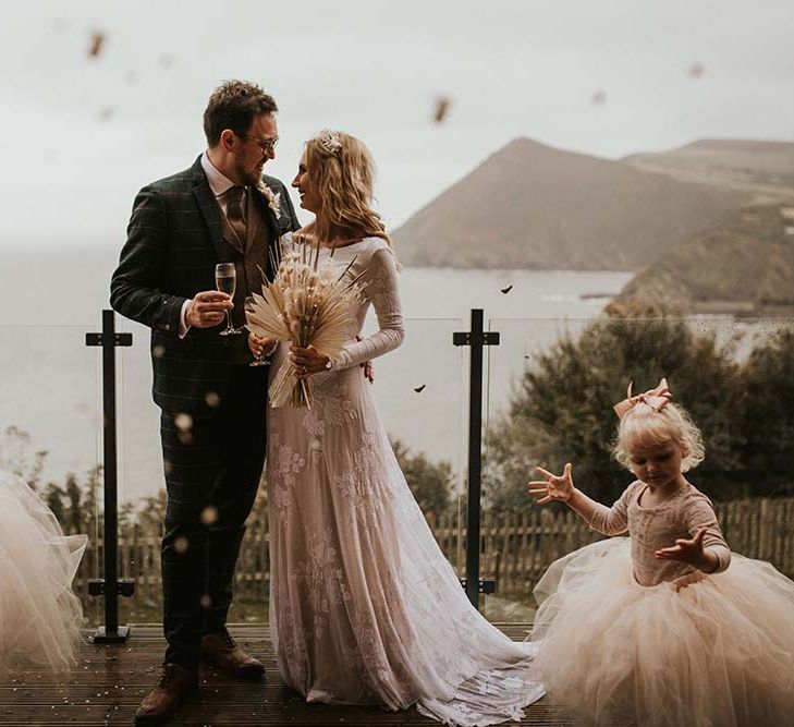 Flower girls in tutus throwing confetti over their mum and dad at intimate Devon wedding 