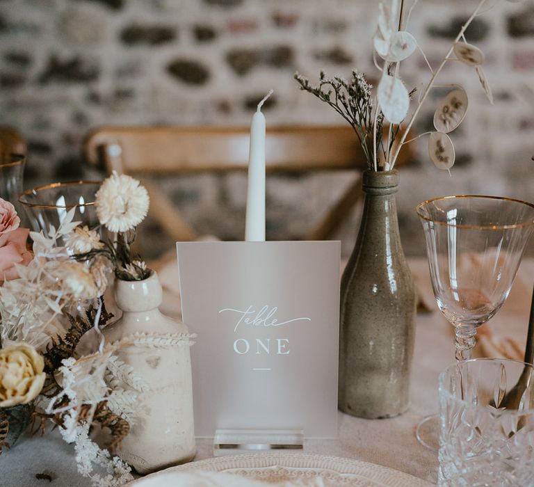 Vellum table sign with white font. Plus, white taper candles and dried flower arrangements in neutral tones 