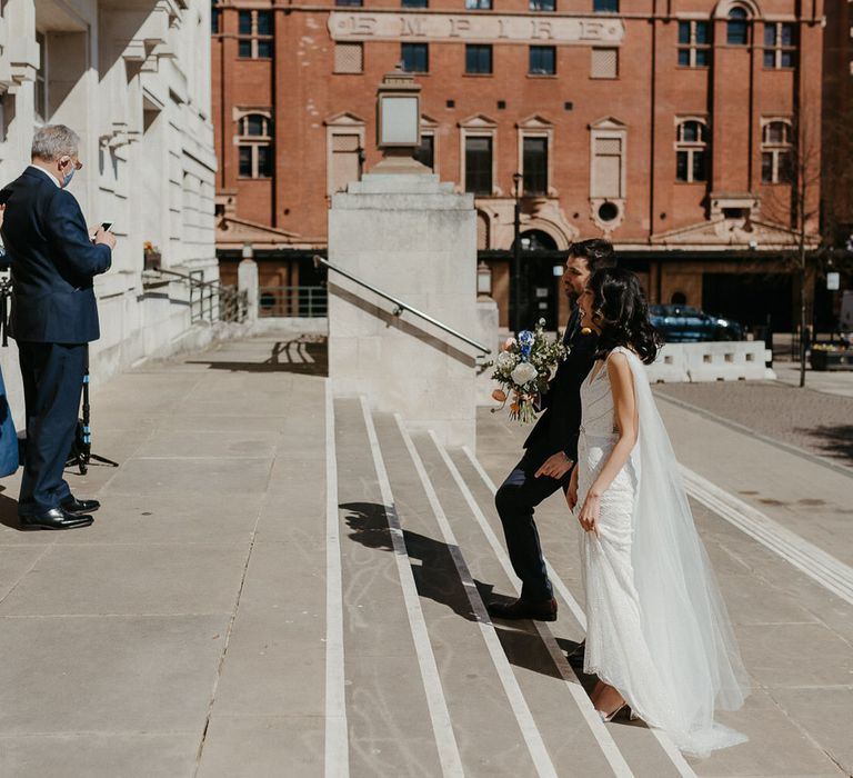 Bride and groom walking up the steps at Hackney Town Hall