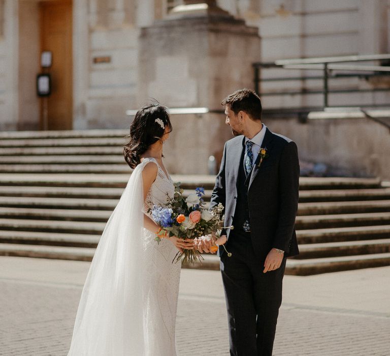 Bride and groom holding hands in front of Hackney Town Hall