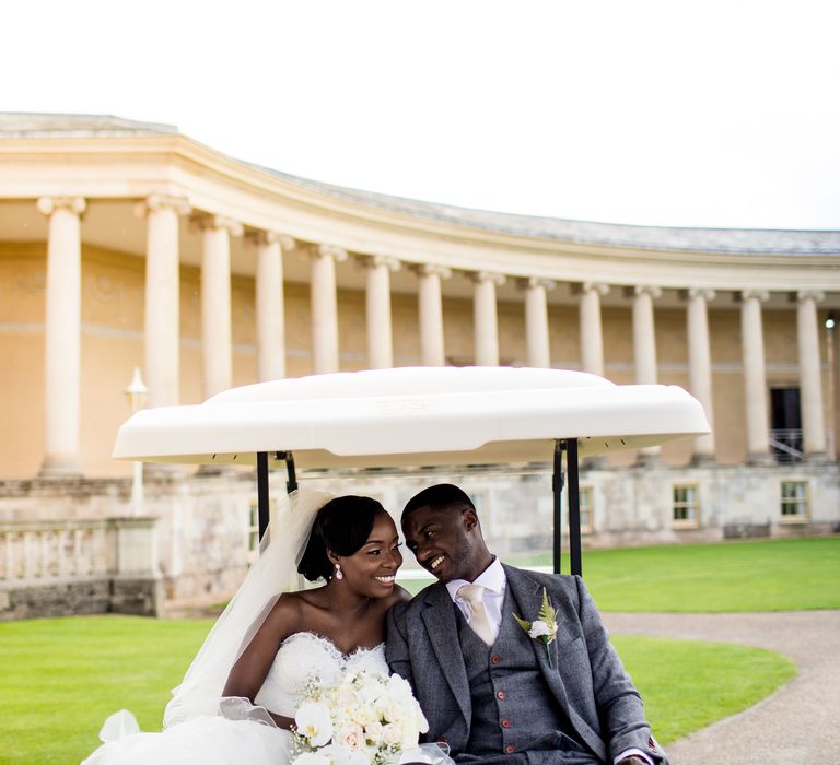 Bride & groom drive in golf cart through the grounds of the Stowe House