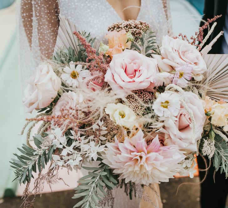 Pastel pink wedding bouquet with roses, dahlias, dried palm leaves and foliage