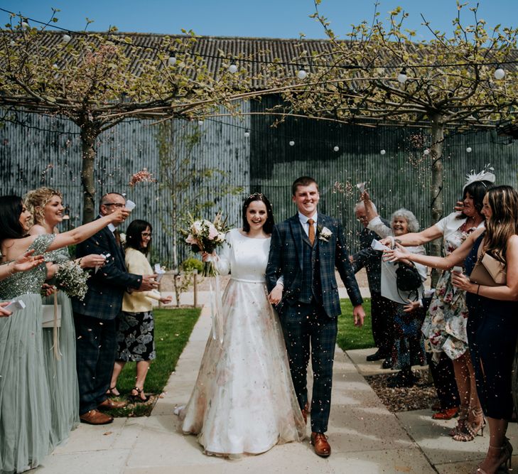 Confetti moment with bride in a floral skirt wedding dress holding a white and green wedding bouquet 