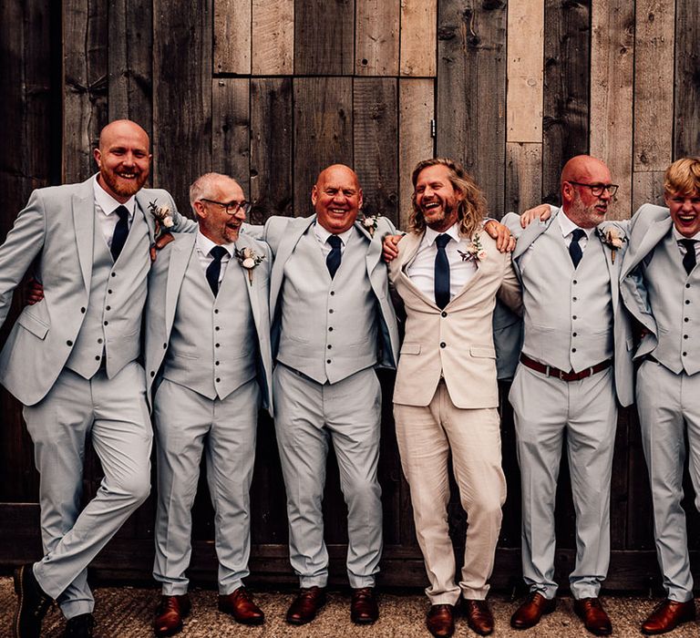 Groom in cream wedding suit with groomsmen in matching pale blue suits