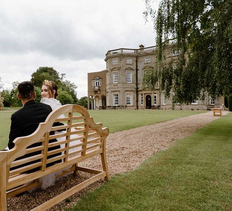 Interabled couple sitting on a bench in the grounds of Bourton Hall wedding venue in Warwickshire 